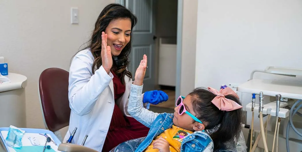 Sunnyvale, TX dentist Dr. Nessa Pathiyil high-fiving one of her pediatric dental patients